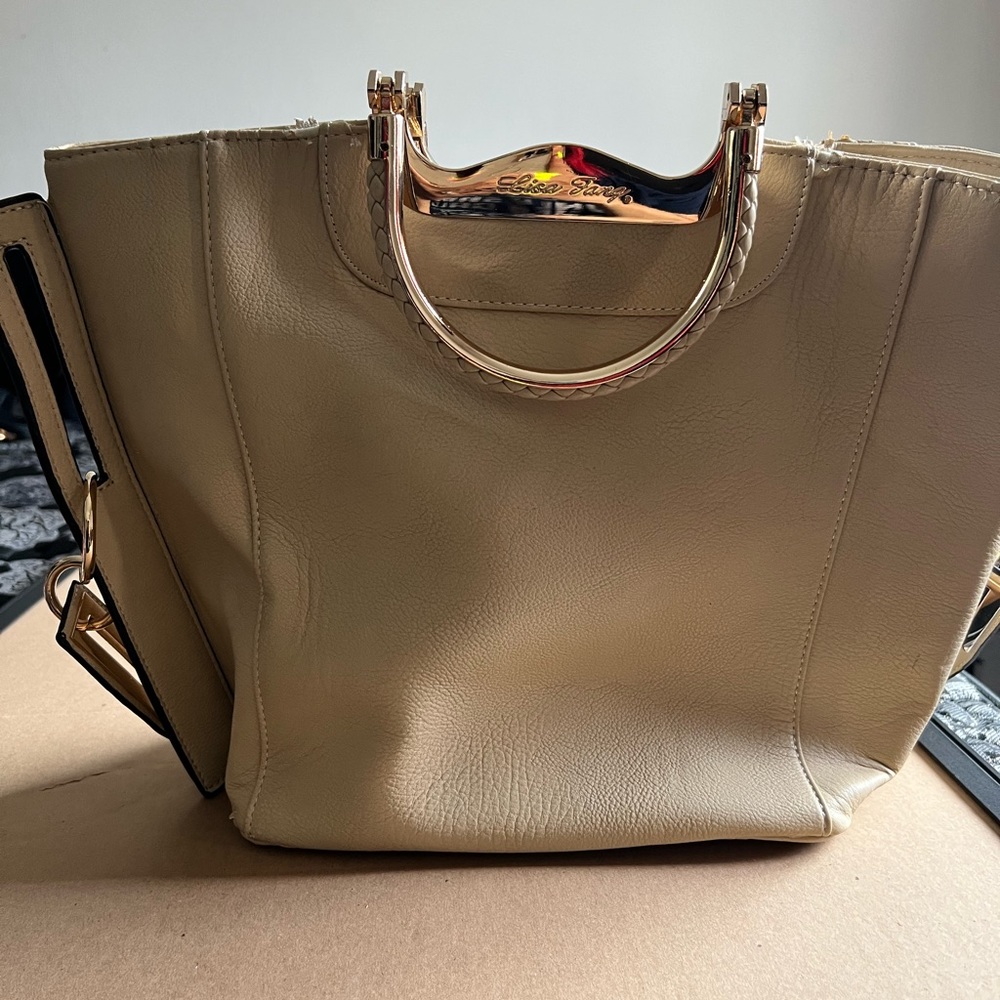 Large tan handbag and with gold handles.
